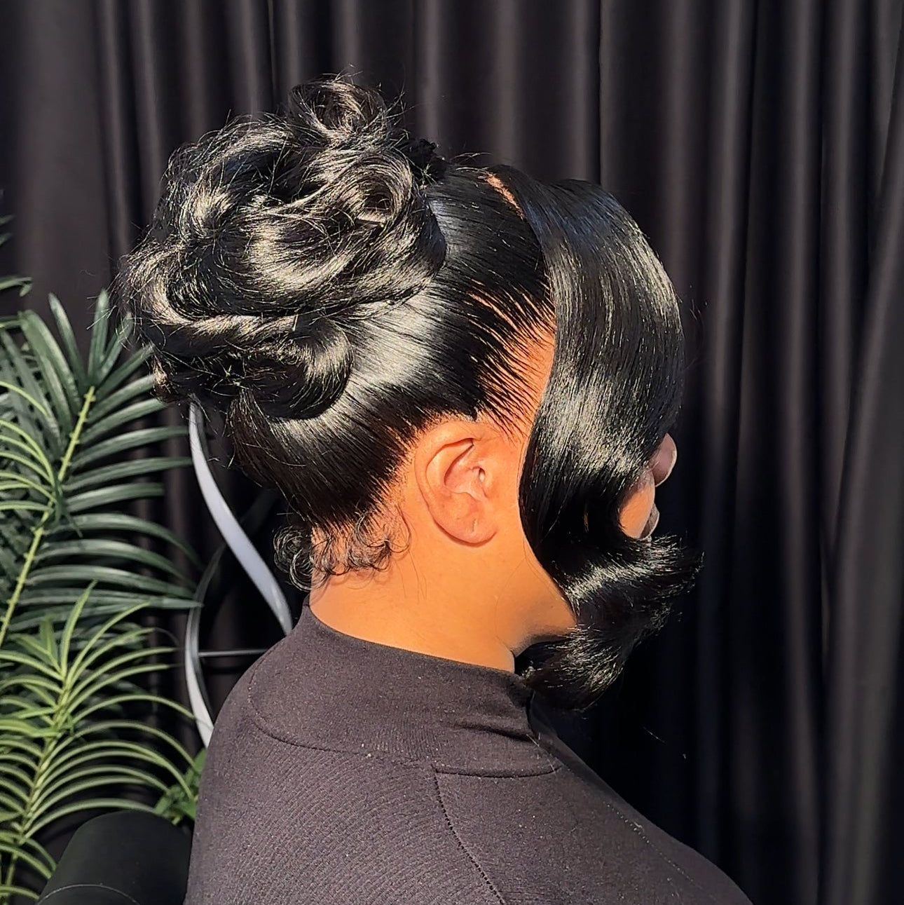 Person with styled hair against a dark curtain background